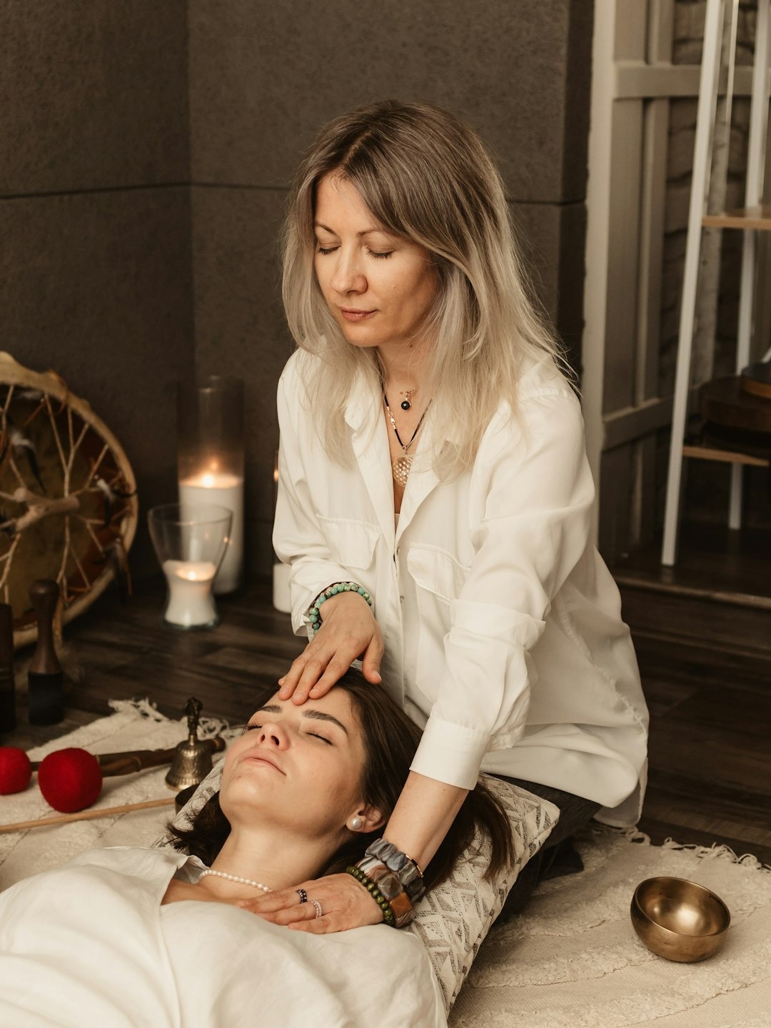 Practitioner performing energy healing on a client lying on a rug.